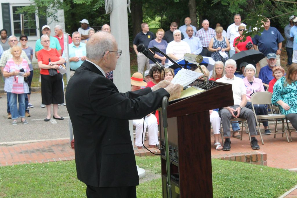 A man in formal wear reading a speech in front of an audience in Windsor Bertie.
